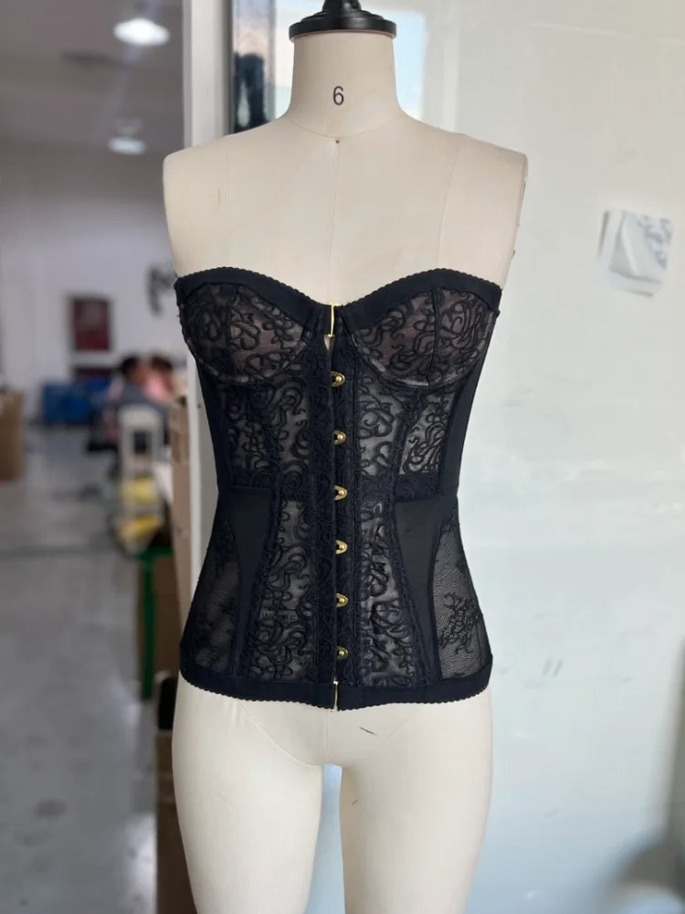 Top tipo corsé ajustado para mujer con encaje y diseño calado. Sin mangas y sin tirantes, con ajuste de cordones para realzar la figura. Estilo sexy y moderno, tendencia streetwear verano 2026.