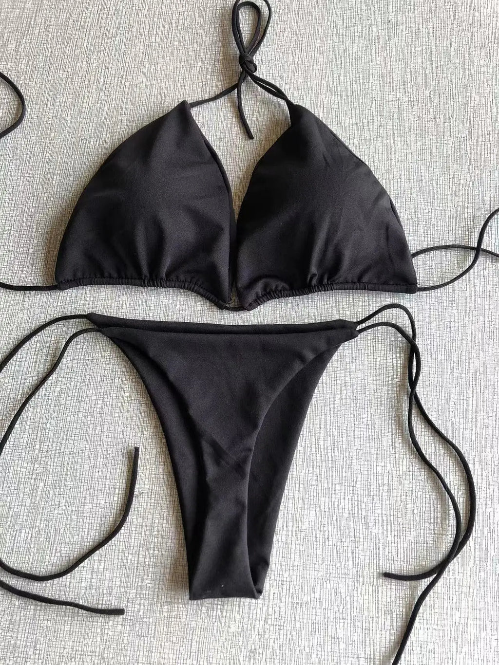 Bikini de dos piezas para mujer con top triangular. Diseño con atado tipo halter ajustable. Incluye braguita tipo tanga, ideal para playa y verano. Estilo moderno y sensual para beachwear.