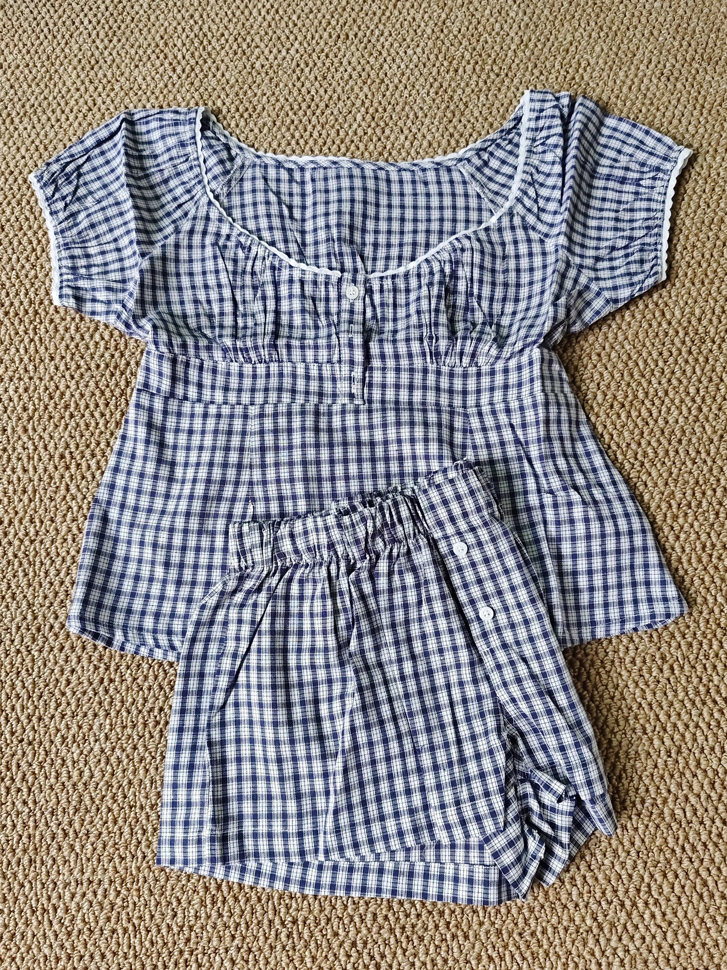 Conjunto de verano para mujer de 2 piezas, compuesto por una blusa de cuadros rojos con mangas abullonadas y detalle de amarre, acompañada de shorts de algodón con botones y cintura elástica. Fresco, cómodo y perfecto para un look femenino y moderno.