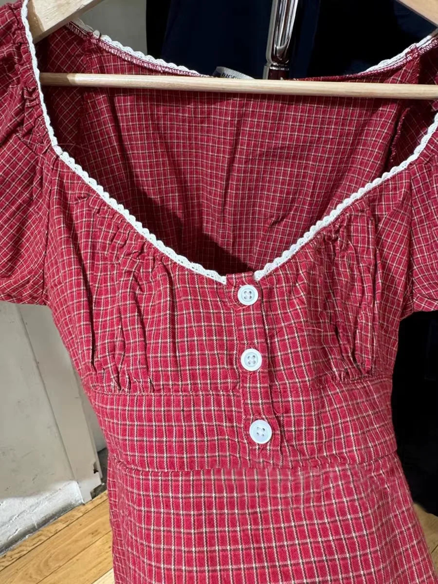 Conjunto de verano para mujer de 2 piezas, compuesto por una blusa de cuadros rojos con mangas abullonadas y detalle de amarre, acompañada de shorts de algodón con botones y cintura elástica. Fresco, cómodo y perfecto para un look femenino y moderno.