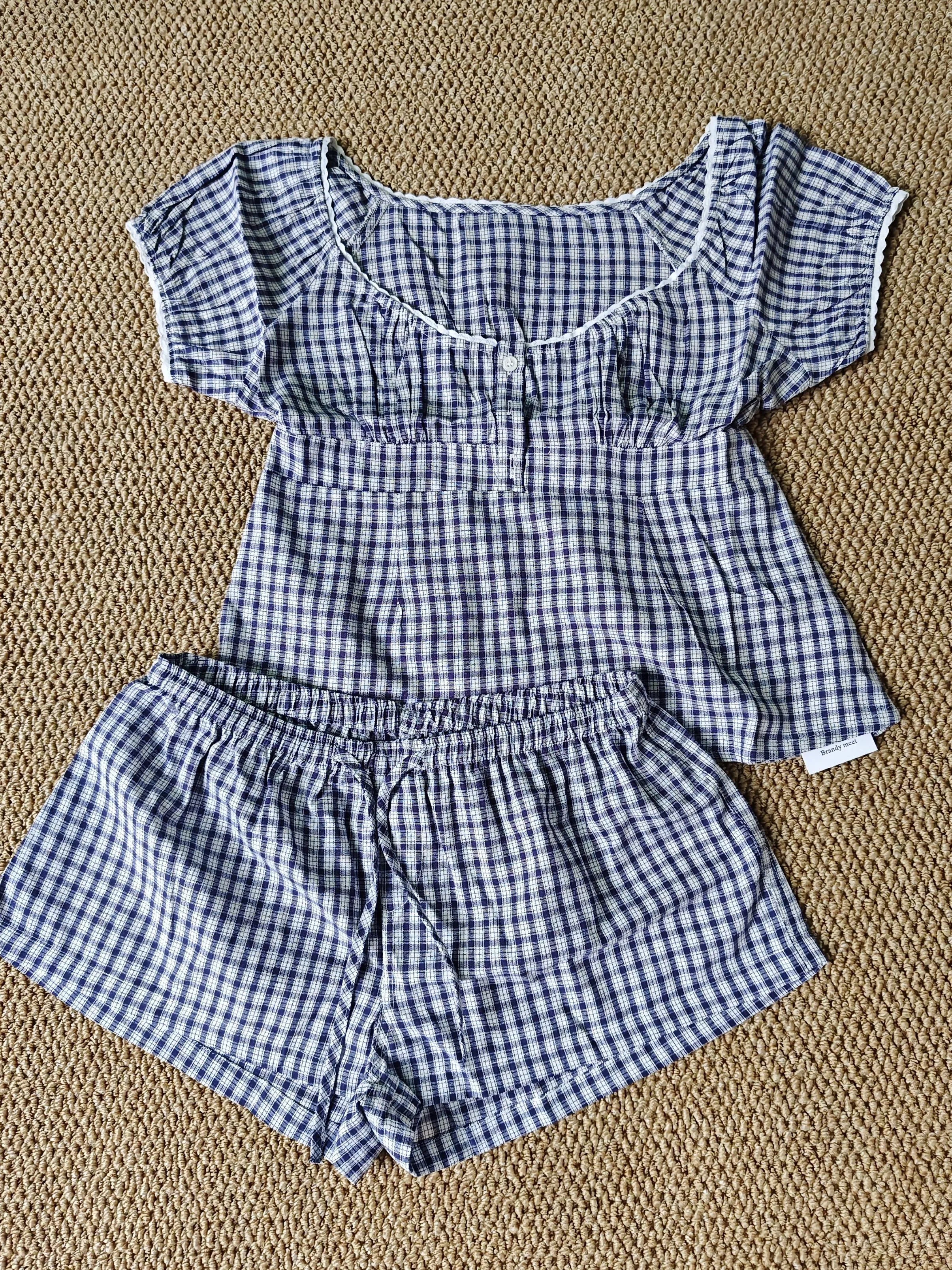 Conjunto de verano para mujer de 2 piezas, compuesto por una blusa de cuadros rojos con mangas abullonadas y detalle de amarre, acompañada de shorts de algodón con botones y cintura elástica. Fresco, cómodo y perfecto para un look femenino y moderno.