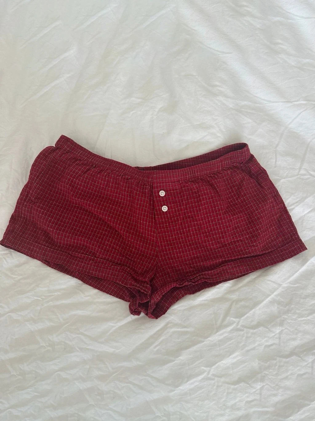 Conjunto de verano para mujer de 2 piezas, compuesto por una blusa de cuadros rojos con mangas abullonadas y detalle de amarre, acompañada de shorts de algodón con botones y cintura elástica. Fresco, cómodo y perfecto para un look femenino y moderno.