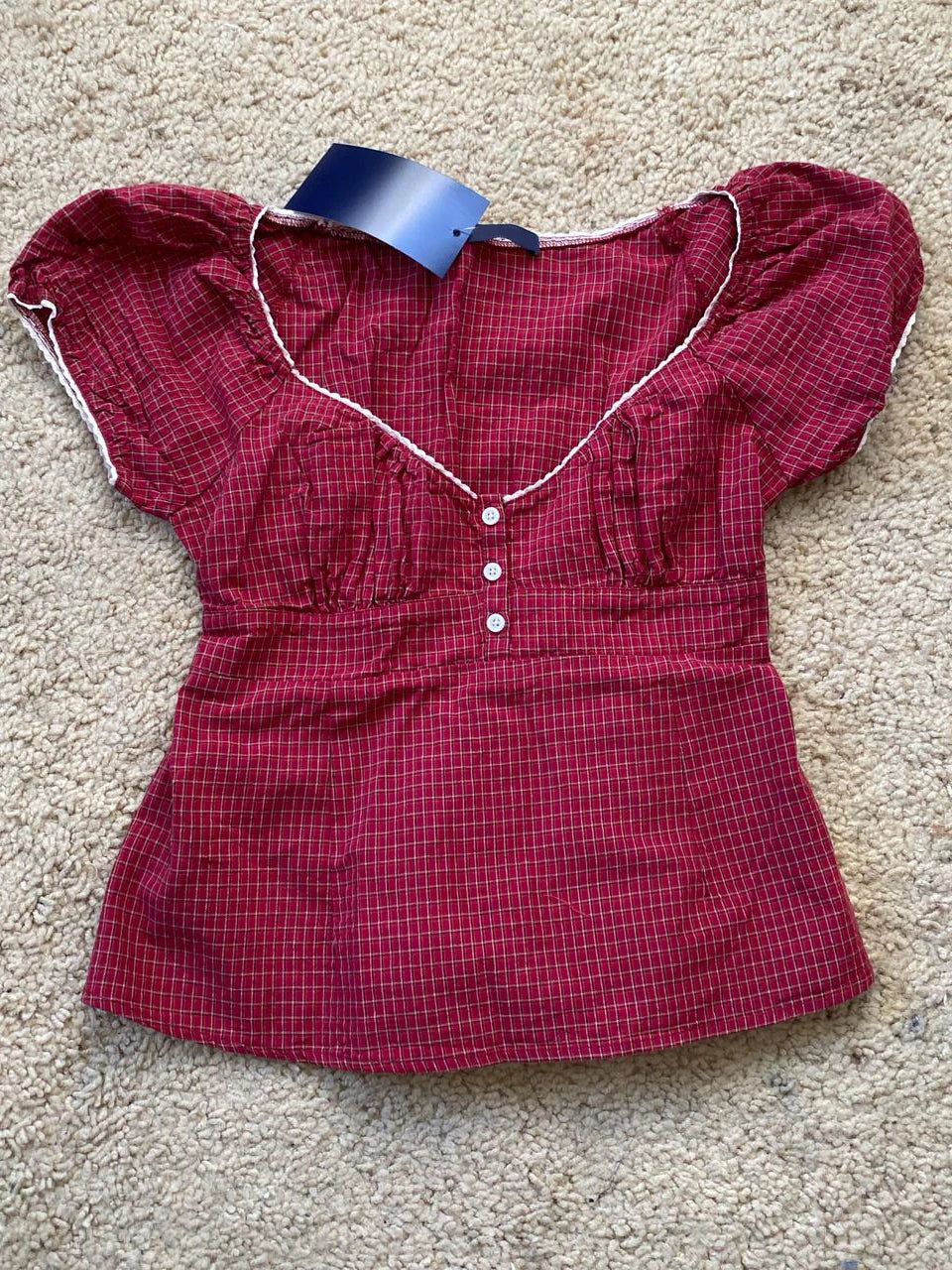 Conjunto de verano para mujer de 2 piezas, compuesto por una blusa de cuadros rojos con mangas abullonadas y detalle de amarre, acompañada de shorts de algodón con botones y cintura elástica. Fresco, cómodo y perfecto para un look femenino y moderno.